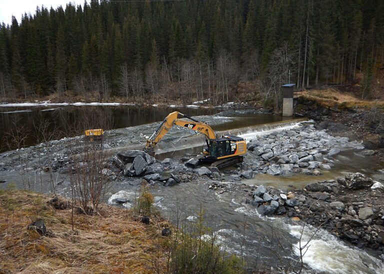 På nedsida av den forsterka terskelen ved Sjøforsbrua legges støre steiner for å motvirke graving av vannmassene. Øijord & Aanes entreprenører er utførende