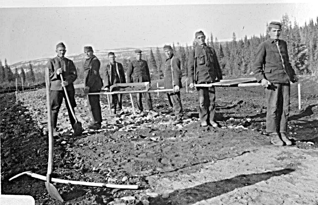 Autentisk bilde fra 1943, der jugoslaviske krigsfanger, tydelig oppstilt til fotografering, viser sine arbeidsredskaper og veidekket de har laga. Fra området på nordsida av Korgfjellet, 2-3 km fra Korgen.