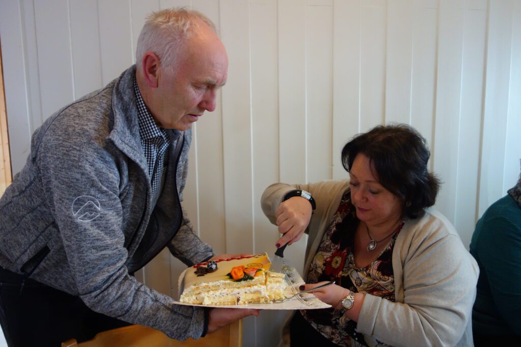 Lederen i menighetsrådet forsyner ordføreren med kake