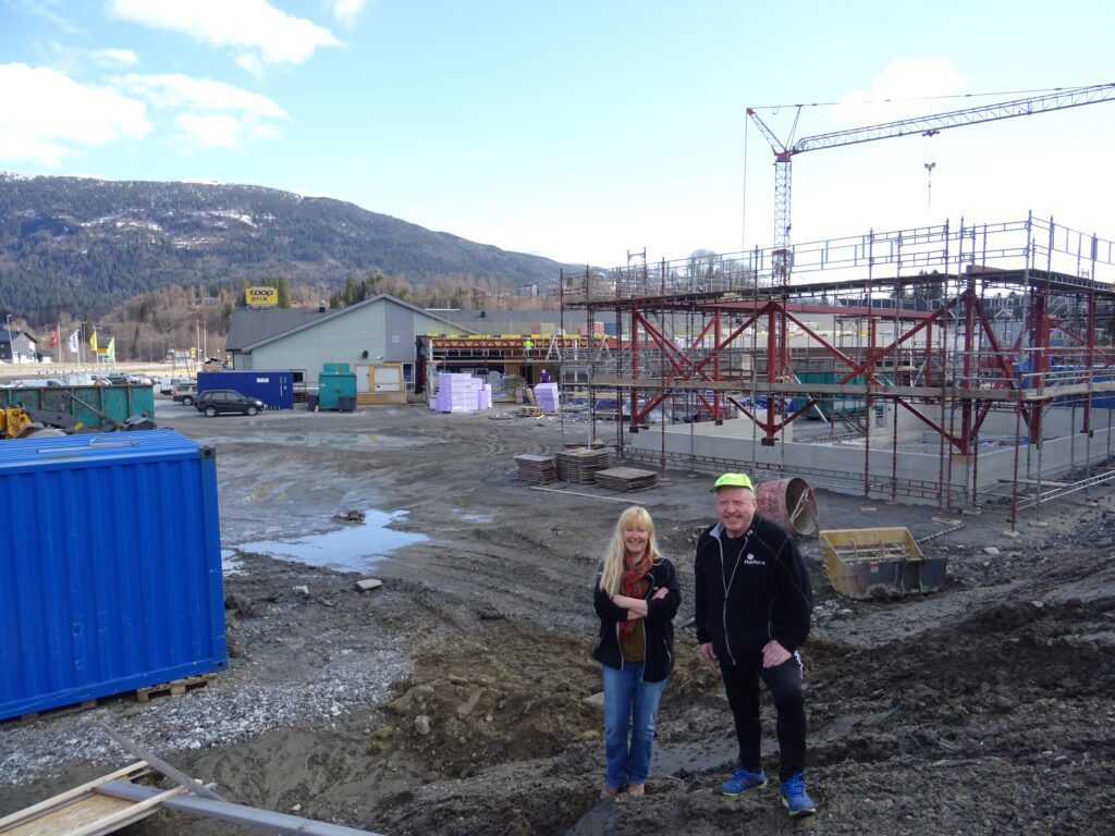 Ingrid Thom og Arnulf Skreslett inspiserer det nye uteområdet for Coop Korgen. Bak skimtes tilbygget, bak skjellettet til Byggmixhuset. I området containerne skal det bli ladestasjoner for elbiler.