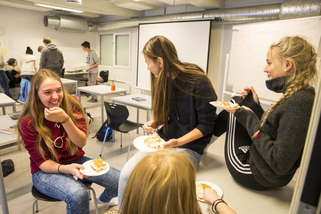 Jentene Rikke, Victoria og Andrea Sofie koser seg med kake i norsktimen. Andrea Sofie forteller at hun nettopp har startet på en bok på over 400 sider, og regner med å bli ferdig om noen uker.