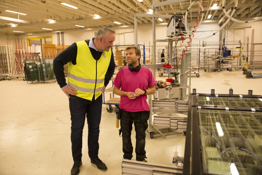 Daglig leder i Natre Vinduer AS, Frode Henning Killi i samtale med Eskil Jørgensen i produksjonshallen. På nyåret øker antall produksjonstimer kraftig når det innføres to skift.