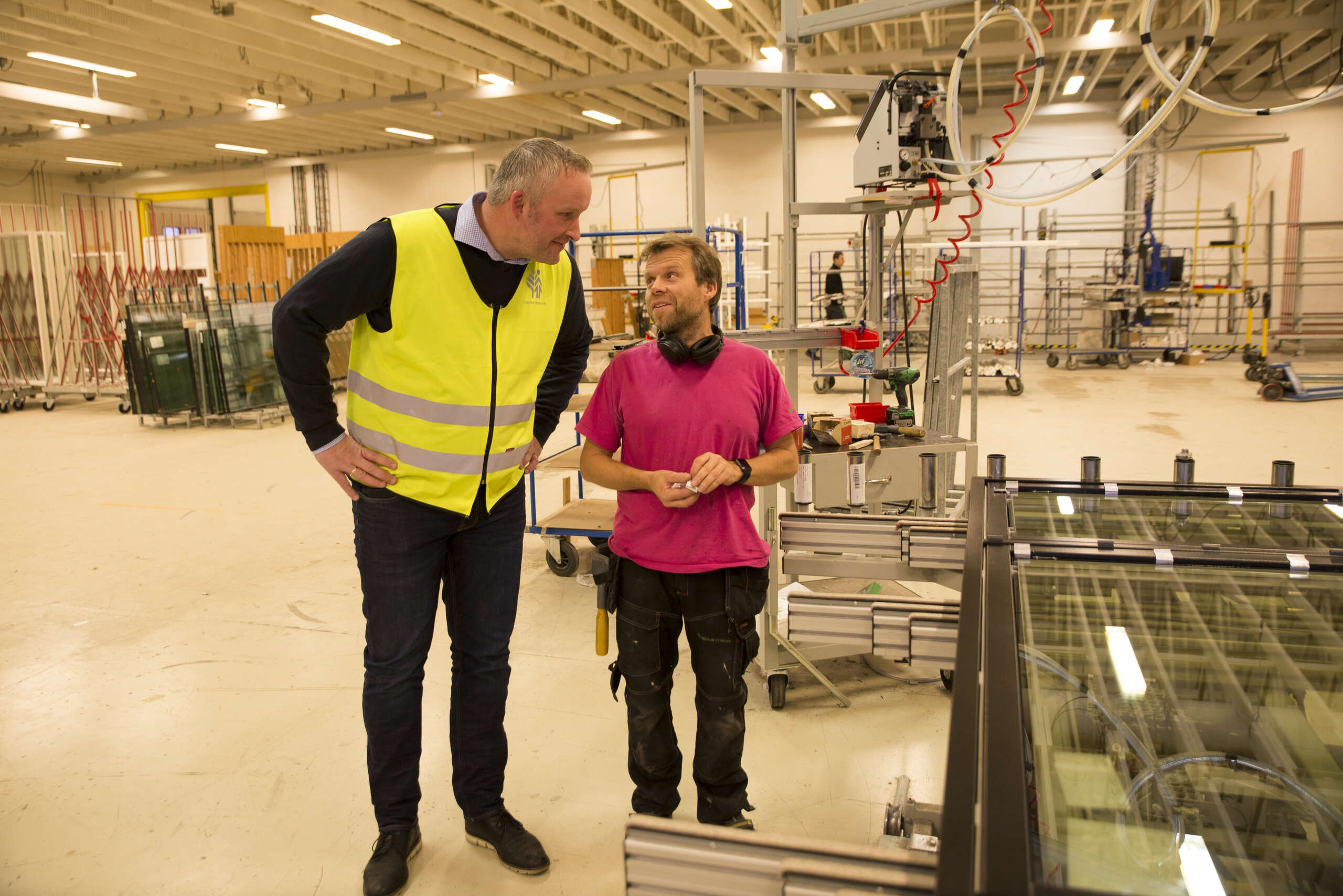 Daglig leder i Natre Vinduer AS, Frode Henning Killi i samtale med Eskil Jørgensen i produksjonshallen. På nyåret øker antall produksjonstimer kraftig når det innføres to skift.