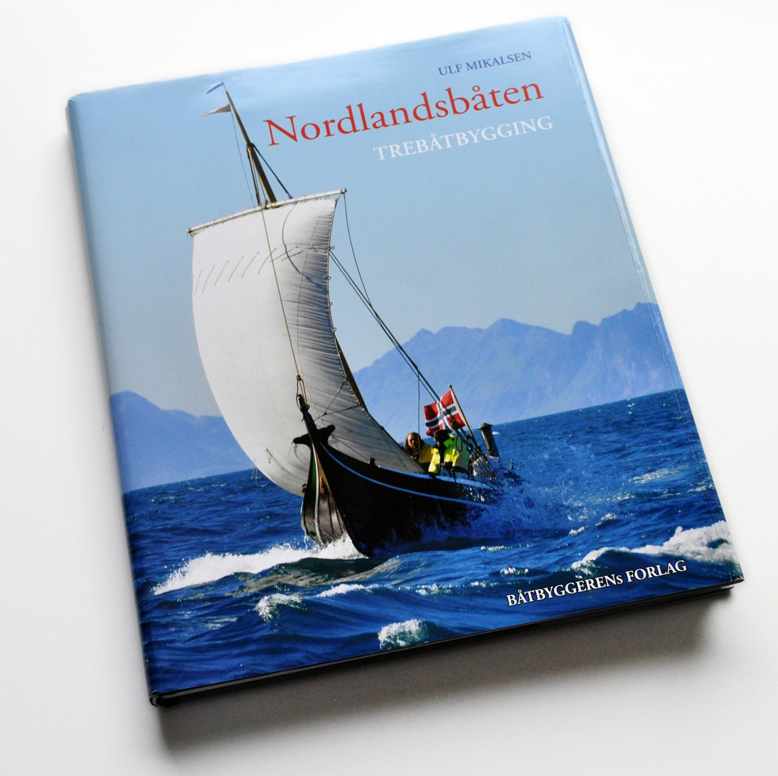Praktboka er på 266 sider og den har ytre mål på omlag 29x24 cm.|Mannen bak praktboka er "Båtbyggern på Kjerringøy" Ulf Bjørnar Mikalsen.|Boka er grundig spekket med historikk om nordlandsbåtens utvikling.|Boka er også ei grundig instruksjonsbok for den som vil bygge en nordlandsbåt.|Mange flotte og store fargebilder på godt papir preger boka. Her et bilde av "Hemnes" da den ble sjøsatt på Hemnesberget i 2015.|Sommeren 2015 fikk Gøril Vandbak Kjærstad (og et par andre) et lite minikurs i bruk av åttring med råsegl utfor Hemnesberget.|Boka er "krydret" med mange store og små illustrasjoner av kunstneren Karl Erik Harr.