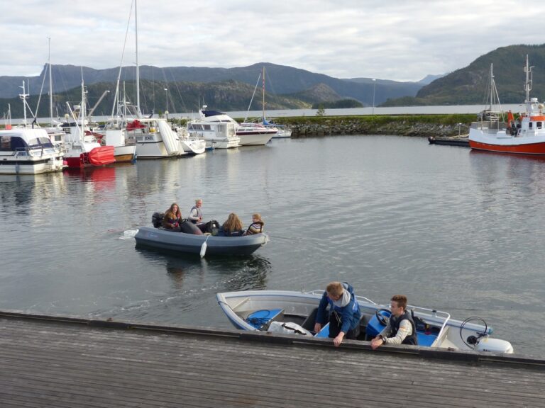 Det ble mange båtturer for få fraktet alle ungdommene med utstyr over til Sundsholmen.|Yngstemann på to år var allerede lagt seg da vi ankom.||Sikkert best slik når mamma Trine og pappa Antoine mest brydde seg om de større barna/ungdommene.|Men sure er de slettes ikke. Vera Gårdvik og Emilie Pettersen Nygård gjør klar og tester ut soveplassen.|Det var fin og koselig stemning rundt bålplassen mens de ventet på varme muffins.|Trine Kosmo og Torunn Øvrevoll fortalte en del omkring oppstarten og driften av tur og fjellsportgruppa.