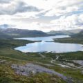 Kjennsvatnet sett fra sør. Nede til høyre ser vi anleggsvirksomheten ved etableringen av Kjensvatn kraftstasjon.|Bussen kom seg ikke lenger enn til utløpet av Kjennsvatnet. Delegasjonen tar beina fatt for å se på forholdene.|Rune Trettbakk er leder i TMU i Hemnes og tok mikrofonen for å fremme kravene fra Hemnes kommune.