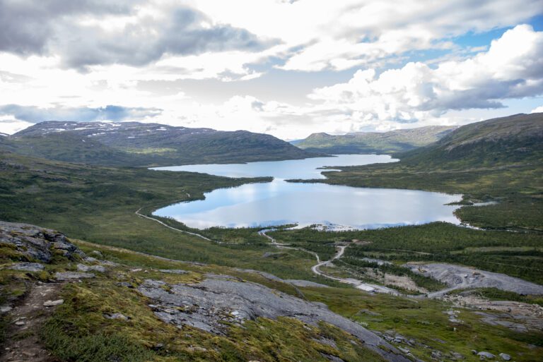 Kjennsvatnet sett fra sør. Nede til høyre ser vi anleggsvirksomheten ved etableringen av Kjensvatn kraftstasjon.|Bussen kom seg ikke lenger enn til utløpet av Kjennsvatnet. Delegasjonen tar beina fatt for å se på forholdene.|Rune Trettbakk er leder i TMU i Hemnes og tok mikrofonen for å fremme kravene fra Hemnes kommune.