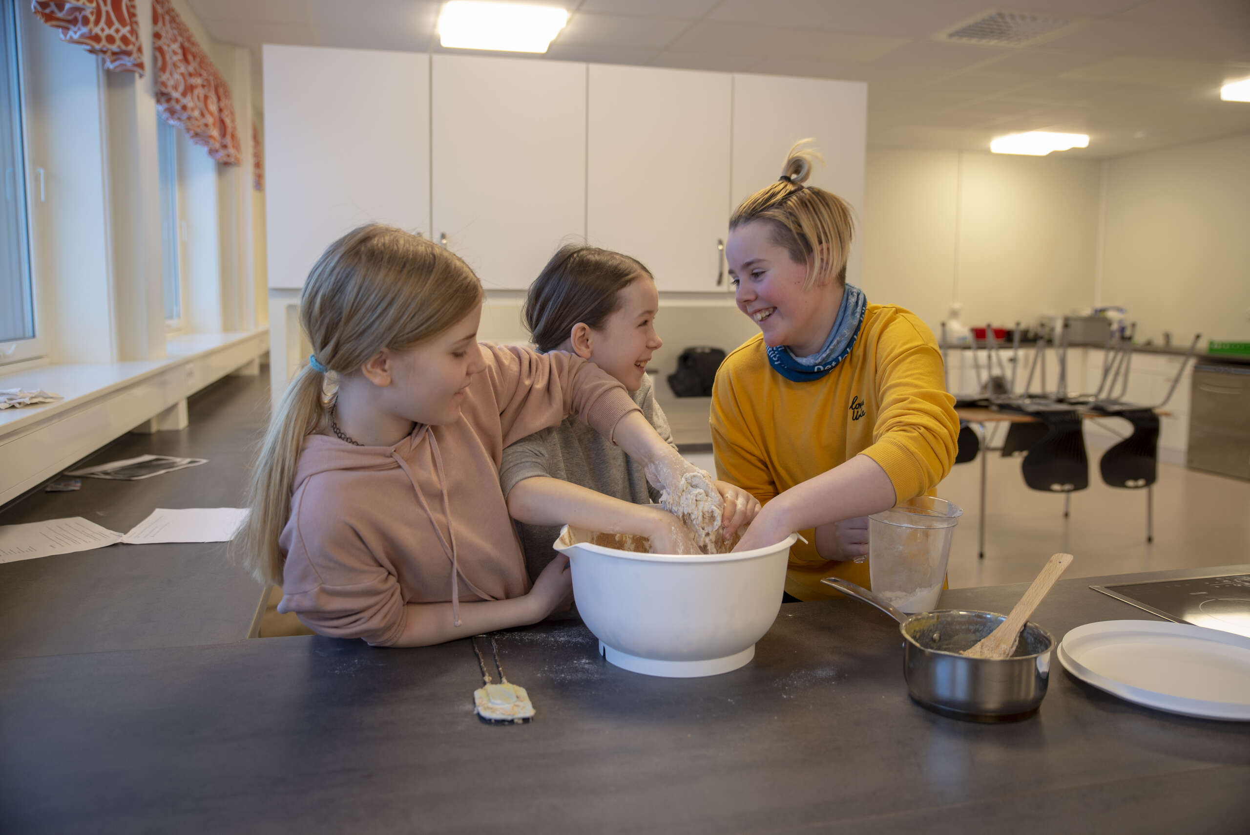 Andrea Lillevold, Rose Berg-Hansen og Aimee Sørgård samarbeider om å elte deigen.