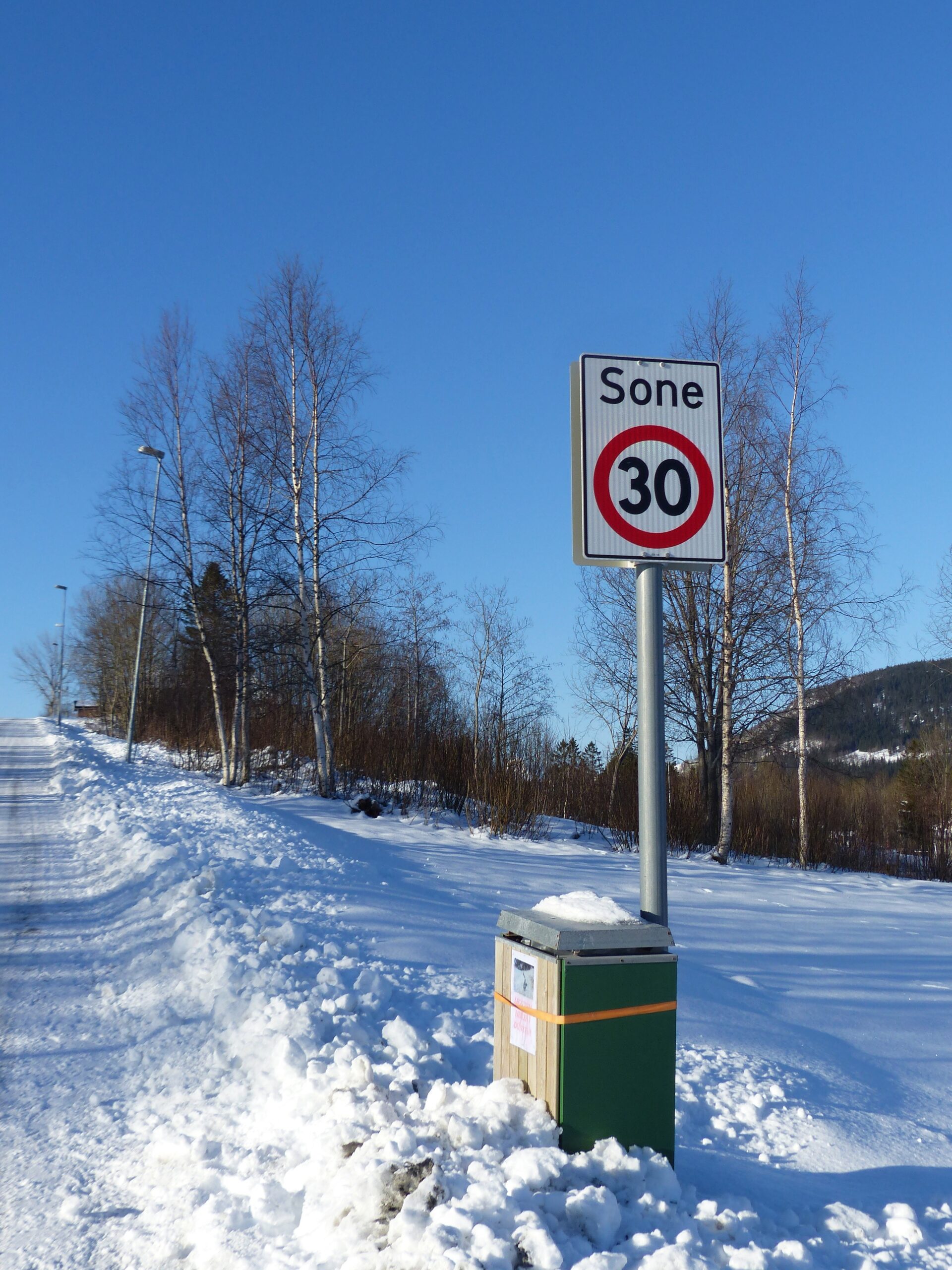 Her er en av dunkene uplassert i krysset mellom Juvikveien og Myraveien. Godt forankret til et skilt for lavere fart slik at den svarte posen kan legges i dunken.