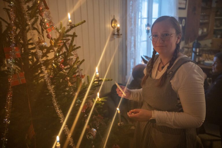 Oddrun Sæbø tenner levende lys på juletreet hos Inderdalen Gård, noe man ikke ser i bruk ofte i dag.